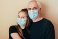 Granddaughter in a protective mask hugs her grandfather and cheers him up at a difficult time of limitations due to a sudden outbr