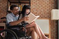 Granddaughter sat on the old Asian grandfather`s lap in wheelchair