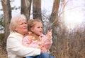 Granddaughter sitting in grandmother`s lap. Happy family.  Having good times with grandparent outdoors Royalty Free Stock Photo