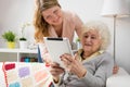 Granddaughter teaching grandma how to use tablet computer