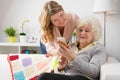 Granddaughter teaching grandma how to usemodern cell phone