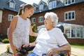 Granddaughter Visiting Grandmother Sitting In Motorized Wheelchair In Retirement Home Royalty Free Stock Photo