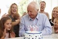 Grandfather Blows Out Birthday Cake Candles At Family Party Royalty Free Stock Photo