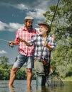 Grandfather and boy fishing together. Happy father and son fishing in river holding fishing rods. Brown trout fish Royalty Free Stock Photo