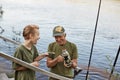 Grandfather and boy fishing together, boy and old man standing with fishing rod, drinking hot beverage from thermos, spending time Royalty Free Stock Photo