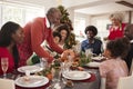Grandfather bringing the roast turkey to the dinner table during a multi generation, mixed race family Christmas celebration, clos Royalty Free Stock Photo