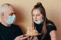 Grandfather with care gives a Caucasian girl a birthday cake and granddaughter blows out candles, enjoy the holiday during quarant Royalty Free Stock Photo