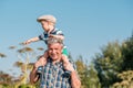 Grandfather carries grandson toddler boy on his shoulders Royalty Free Stock Photo