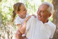 Grandfather carrying granddaughter piggyback in the forest