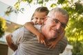 Grandfather carrying granddaughter piggyback. Looking at camera