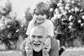 Grandfather carrying his grandson having fun in the park at the sunset time. Family tradition. Father son and Royalty Free Stock Photo