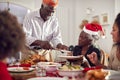 Grandfather Carving And Serving As Multi Generation Family Enjoy Eating Christmas Meal At Home