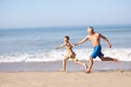 Grandfather chasing young boy on beach