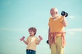 Grandfather and child lifting dumbbell. Lifting dumbbells. Smiling little boy and happy handsome old man exercising with
