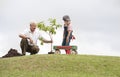 Grandfather and child planting tree in park family togetherness