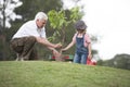 Grandfather and child planting tree in park family togetherness Royalty Free Stock Photo