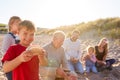 Grandfather Cooking As Multi-Generation Family Having Evening Barbecue Around Fire On Beach Vacation Royalty Free Stock Photo
