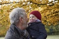 Grandfather Cuddling Granddaughter On Autumn Walk