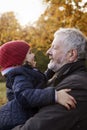 Grandfather Cuddling Granddaughter On Autumn Walk