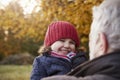 Grandfather Cuddling Granddaughter On Autumn Walk