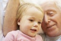 Grandfather Cuddling Granddaughter In Bed