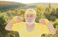 Grandfather exercising with dumbbell. Sport for senior man. Senior man in park working out with weights. Royalty Free Stock Photo