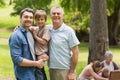 Grandfather father and son with family in background at park