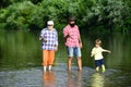 Grandfather, father and son are fly fishing on river. Family bonding. Summer day. Man teaching kids how to fish in river Royalty Free Stock Photo