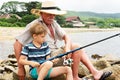 Grandfather fisher in straw hat and little male grandkid enjoying leisure activity use fishing rod Royalty Free Stock Photo