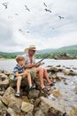 Grandfather fisher in straw hat and little male grandkid enjoying leisure activity use fishing rod Royalty Free Stock Photo