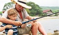 Grandfather fisher in straw hat and little male grandkid enjoying leisure activity use fishing rod Royalty Free Stock Photo