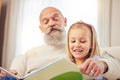 Grandfather, girl and family reading in a house with learning and child development at home. Books, story and education