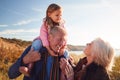 Grandfather Giving Granddaughter Ride On Shoulders As They Walk Through Sand Dunes With Grandmother Royalty Free Stock Photo