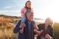 Grandfather Giving Granddaughter Ride On Shoulders As They Walk Through Sand Dunes With Grandmother Royalty Free Stock Photo