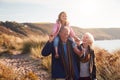 Grandfather Giving Granddaughter Ride On Shoulders As They Walk Through Sand Dunes With Grandmother Royalty Free Stock Photo