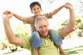 Grandfather Giving Grandson Ride On Back In Park Royalty Free Stock Photo