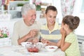 Grandfather and grandchildren eating fresh strawberries at kitch Royalty Free Stock Photo