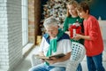 Grandfather and grandchildren in a room decorated for Christmas against the background of a Christmas tree. Royalty Free Stock Photo