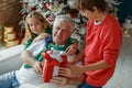 Grandfather and grandchildren in a room decorated for Christmas against the background of a Christmas tree. Royalty Free Stock Photo