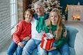 Grandfather and grandchildren in a room decorated for Christmas against the background of a Christmas tree. Royalty Free Stock Photo