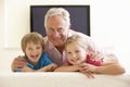 Grandfather And Grandchildren Watching Widescreen TV At Home Royalty Free Stock Photo