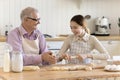 Grandfather and granddaughter prepare homemade buns in the kitchen