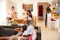 Grandfather With Granddaughter Sitting On Sofa At Home Watching Movie With Family In Background Royalty Free Stock Photo