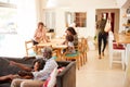 Grandfather With Granddaughter Sitting On Sofa At Home Watching Movie With Family In Background Royalty Free Stock Photo