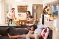 Grandfather With Granddaughter Sitting On Sofa At Home Watching Movie With Family In Background Royalty Free Stock Photo