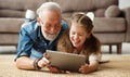 Grandfather and granddaughter using tablet on floor