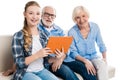 Grandfather, grandmother and grandchild using digital tablet and sitting on sofa Royalty Free Stock Photo