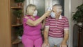 Grandfather and grandmother measures temperature with non-contact infrared thermometer. Coronavirus