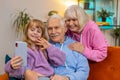 Grandfather grandmother and small granddaughter making video call online on smartphone at home sofa Royalty Free Stock Photo