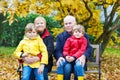 Grandfather, grandmother and two little kid boys, grandchildren sitting in autumn park. Royalty Free Stock Photo